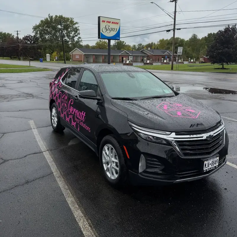 Black Chevrolet Equinox wrapped in pink Gernatt Pest Solutions graphics in a parking lot