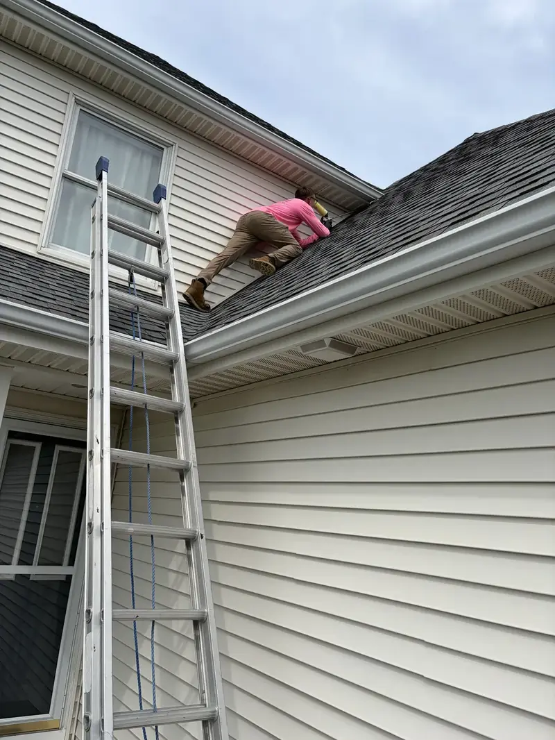 Technician on a roof beside a ladder