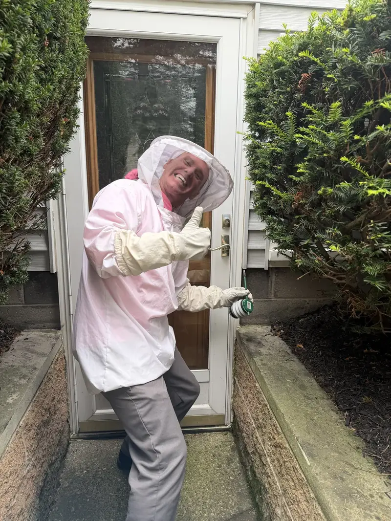 Technician in a protective bee suit giving a thumbs up after a stinging insect job